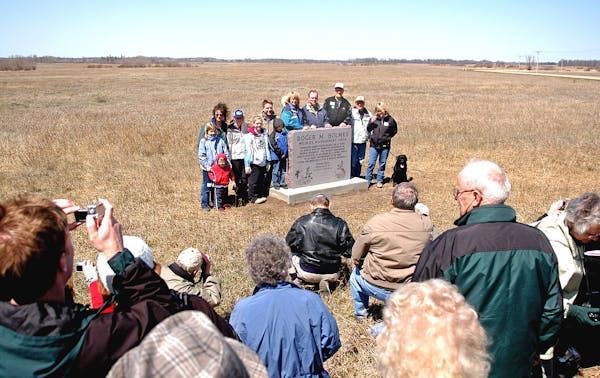 Retired Department of Natural Resources fish and wildlife division director Roger Holmes ( behind monument in dark jacket and white cap) was honored i