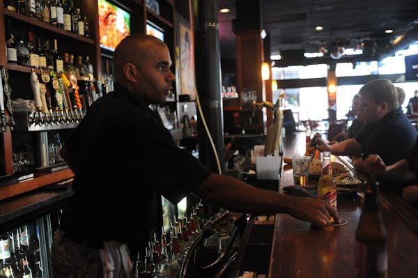 Ari Mlnarik , left, served a beer Tuesday at the Ugly Mug, a bar in downtown Minneapolis. Erik Forsberg, the bar’s owner, said the state-issued card