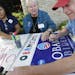On Sunday at DFL headquarters in St. Paul, Rosa Reyes, Mary Jane Hand and Stephen Winkels worked on signs for the president, who is returning to the s