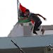 A rebel fighter places the old Libyan flag on the roof of a house in the Abu Salim district in Tripoli, LIbya.