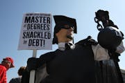 In this Oct. 6, 2011 photo, Gan Golan of Los Angeles, dressed as the "Master of Degrees," holds a ball and chain representing his college loan debt du