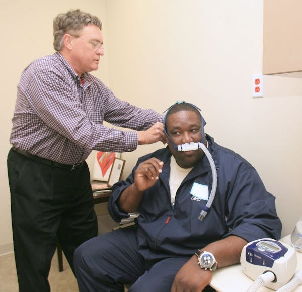 In this 2007 photo, sleep technical Bob Redington, left, helps former Miami Dolphins player Keith Sims put on a Continuous Positive Airway Press Machi