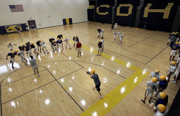 Cretin-Derham Hall football players practiced plays during pre-season in the high school's gym.