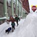 A couple walks past a large snow drift in the Old Port section of Portland, Maine, Saturday, Feb. 9, 2013. Officials are cautioning residents to stay 