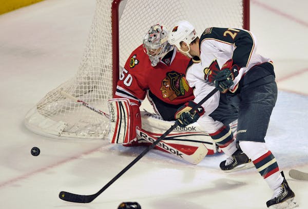 Corey Crawford looks for the puck on a shot by the Wild's Kyle Brodziak during the second period of Game 1