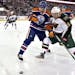 Mikael Granlund and Edmonton Oilers' Eric Belanger scrap for the puck.