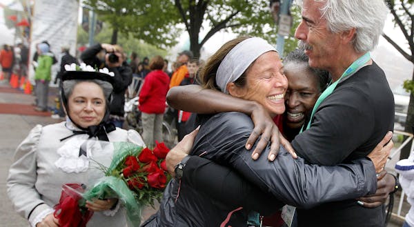 Grandma’s Marathon women’s winner Sarah Kiptoo, middle right, got hugs from her coaches, Vanessa and Scott Robinson of New Mexico, after she cross