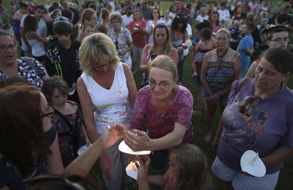 Natalie Koch lit the candle for Judy Hoard, of Centuria, during a vigil for two-year-old Isaiah Theis, who was found dead in a locked car after he wen