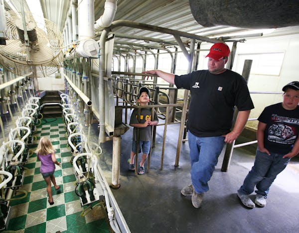 While his children, left to right, Dani, 7, Shayne, 5, and Brett, 10, played in the milking parlor, dairy farmer Harlan Poppler talked about the many 