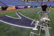 Wayne Enger of the Metrodome grounds crew outlined the Vikings end zone letters with a spray painter on Monday.