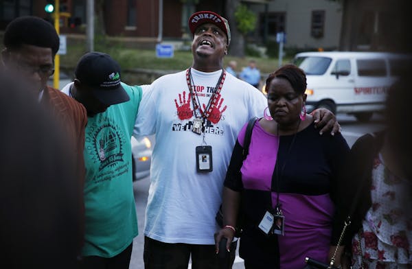 Peace activist K.G. Wilson, center, helped to lead a prayer Tuesday night for the three people shot on the 2900 block of Lyndale Avenue N.