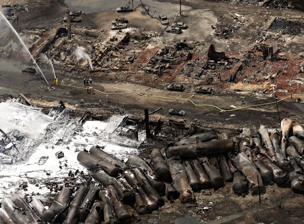 The downtown core lays in ruins as fire fighters continue to water smoldering rubble Sunday, July 7, 2013 in Lac Megantic, Quebec. A runaway train der