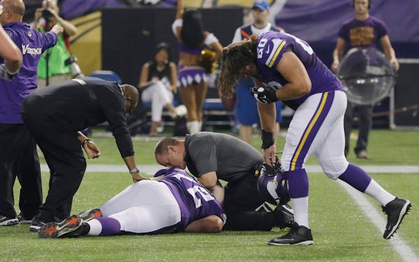 Minnesota Vikings offensive guard Jeff Baca, right, reacts as trainers assist injured Minnesota Vikings guard Seth Olsen.