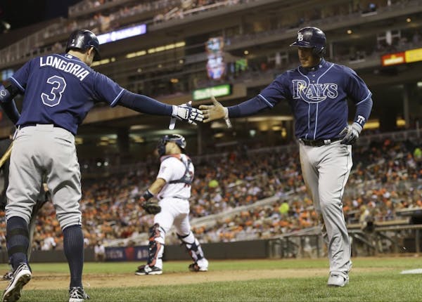 Tampa Bay Rays' Yunel Escobar is greeted by Evan Longoria, left, after he scored from third on a single by James Loney off Minnesota Twins pitcher Kev