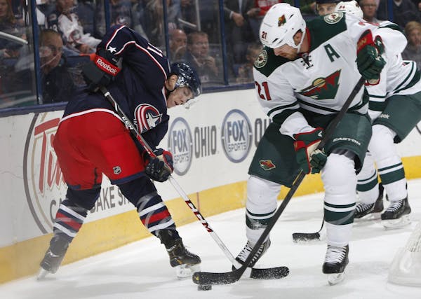 Matt Calvert (left) of the Columbus Blue Jackets is defended by the Wild's Kyle Brodziak (21) during Monday's preseason game. The Wild claimed a 2-1 s