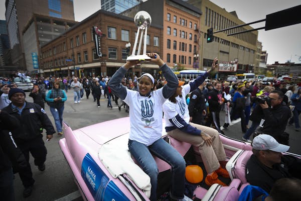 Lynx player Maya Moore held up the championship trophy as she rode a float with Seimone Augustus during a championship celebration parade for the WNBA
