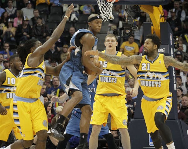 Minnesota Timberwolves forward Corey Brewer, third from left, scoops up a loose ball against Denver Nuggets forwards Kenneth Faried (35) and Wilson Ch