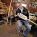 Roger Wold worked on a guitar that he made from his father’s license plate in his garage in Anoka. He makes guitars from cigar-boxes, toilet seats, 