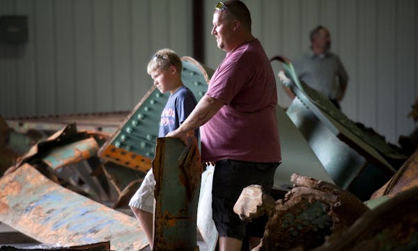 Dave Dahl, right, and his son David, who survived the I-35W bridge collapse with his mom and sister, waited for help to move a large piece of steel th