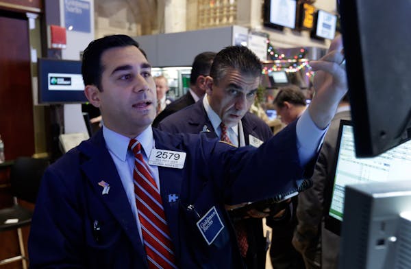 In this Monday, Dec. 16, 2013 photo, specialist William Geier, left, works on the floor of the New York Stock Exchange. Investors took to the sideline