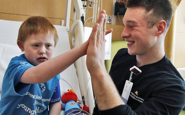 Mike Jones, who is studying to be a nurse, gave patient Alex Whited, 9, of Shakopee, a high-five at the University of Minnesota Amplatz Children’s H