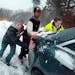 From left, Jason Kleiman, Jared Ballen and Detective Christin Reimann help push a car up a hill after the driver got stuck in snow on Wednesday, Feb. 