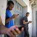 Students gather behind a business looking for a Internet signal for their smart phones in Havana, Cuba, Tuesday, April 1, 2014.
