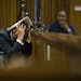Oscar Pistorius covers his head with his hands and a notebook as he listens to forensic evidence during his trial in court in Pretoria, South Africa, 