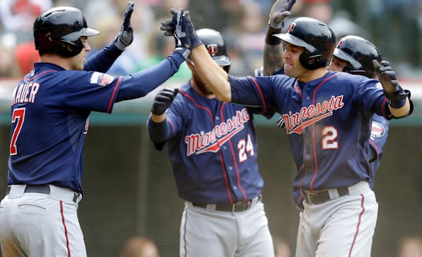 Minnesota's Joe Mauer (7) and Brian Dozier (2) celebrate after scoring on a three-run double from Chris Colabello off Cleveland's Blake Wood during th