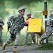 Carrying full gear, including a rifle and handgun, Minnesota National Guard Sgt. Corbin Routier runs towards the finish line after the stress shoot in