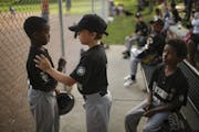 Khy Paradis, 9, center, offered support to Imraan Arale, 9, after his at bat against Kenwood-Bryn Mawr last month at Bryant Square Park. Ashraf Mohame