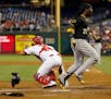 Pittsburgh Pirates' Andrew McCutchen, right, scores past Philadelphia Phillies catcher Wil Nieves after hitting an inside-the-park home run during the