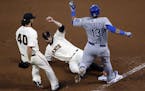 Kansas City Royals' Salvador Perez is out at first on the sliding tag of San Francisco Giants' Brandon Belt (9) Madison Bumgarner moves in to assist, 