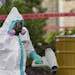 A hazmat worker clean outside the apartment building of a hospital worker who contracted the Ebola virus while caring for a patient, Sunday, Oct. 12, 