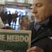 Jean Paul Bierlein reads the latest issue of Charlie Hebdo outside a newsstand in Nice, southeastern France, Wednesday, Jan. 14, 2015. In an emotional