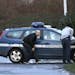 A police officer takes shelter behind a gendarme car in Dammartin-en-Goele, northeast of Paris, where the two brothers suspected in a deadly terror at
