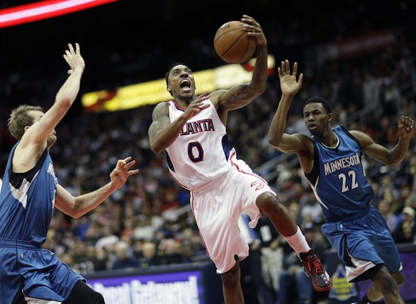 Atlanta Hawks' Jeff Teague, center, shoot against the defense of Minnesota Timberwolves' Robbie Hummel, left, and Andrew Wiggins, right, in the second