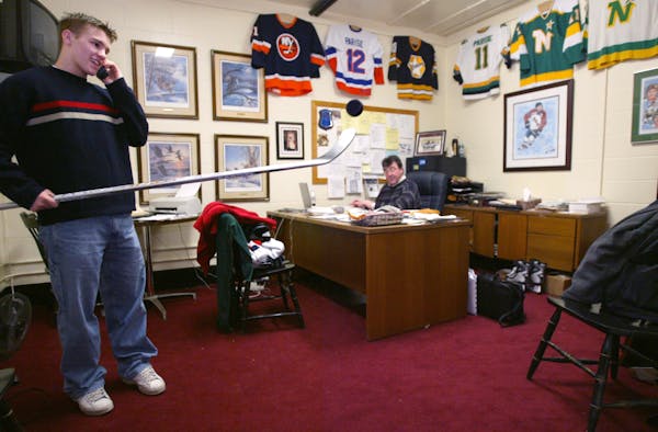 In this 2003 file photo, University of North Dakota star Zach Parise talks with a friend on the phone and plays with a puck in his father J.P. Parise'