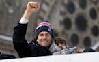 New England Patriots quarterback Tom Brady holds his son Benjamin, right, as he waves during a parade in Boston Wednesday, Feb. 4, 2015, to honor the 