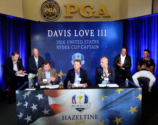 Davis Love III, center, receives applause during a news conference Tuesday, Feb. 24, 2015, at PGA of America headquarters in Palm Beach Gardens, Fla.L
