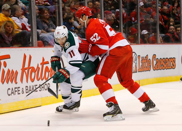 Detroit Red Wings defenseman Jonathan Ericsson (52) defends Minnesota Wild left wing Zach Parise (11) in the first period of an NHL hockey game in Det