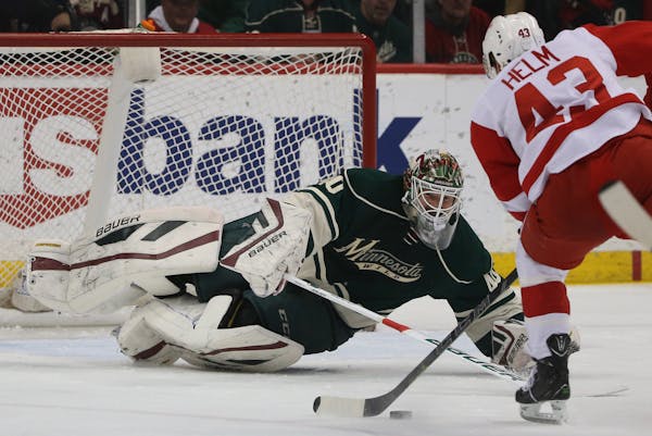Wild goalie Devan Dubnyk made a stop on Detroit’s Darren Helm during Saturday’s game, which was in progress at press time.
