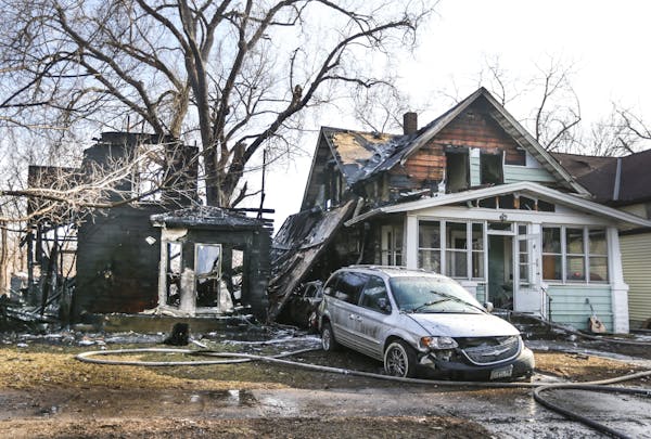 Firefighters worked at the scene of a fire that destroyed two homes in St. Paul on Wednesday when a branch broke off the tree pictured and hit an elec