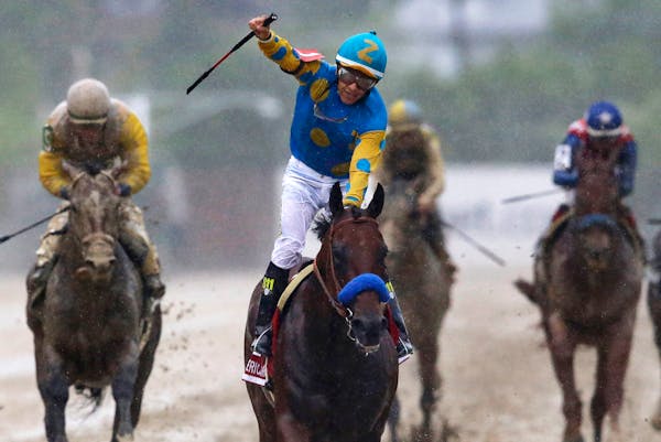 Jockey Victor Espinoza, center, celebrates aboard American Pharoah after winning the 140th Preakness Stakes horse race at Pimlico Race Course, Saturda
