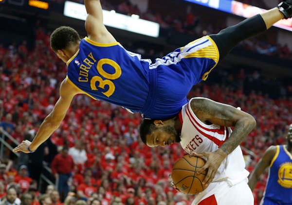 Warriors guard Stephen Curry toppled over Rockets forward Trevor Ariza during the first half in Game 4 of the Western Conference finals Monday. Curry 