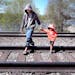 Hmong Vue and nephew Chance Lor, 3, crossed railroad tracks near the spillway in Onalaska, Wis., after fishing at the popular spot.