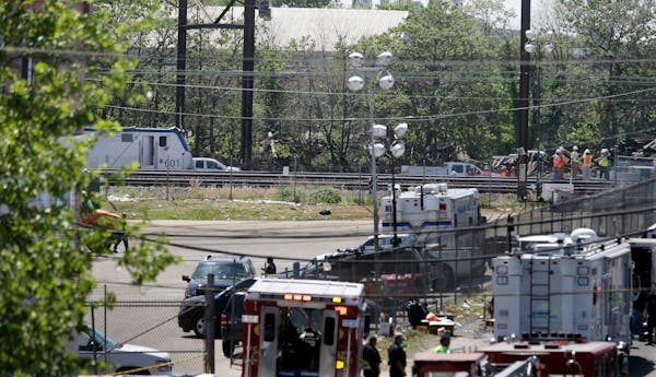 Investigators, right, stand on the tracks near the train engine, left, from Tuesday's deadly train derailment, Thursday, May 14, 2015, in Philadelphia