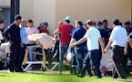 Injured people are treated near the area where an attack took place in Sousse, Tunisia, Friday June 26, 2015. A young man unfurled an umbrella and pul
