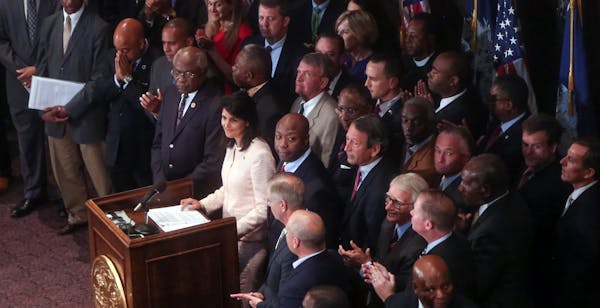 South Carolina Gov. Nikki Haley, middle, is applauded during a news conference in the South Carolina State House, Monday, June 22, 2015, in Columbia, 