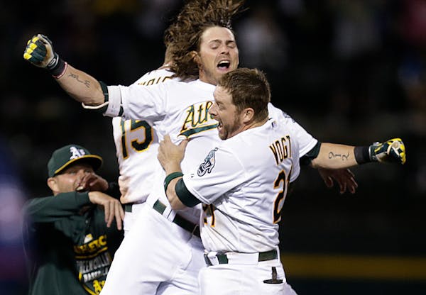 Oakland Athletics' Stephen Vogt (21) and Josh Reddick celebrate after Vogt drove in the winning run against the Minnesota Twins in the 10th inning of 